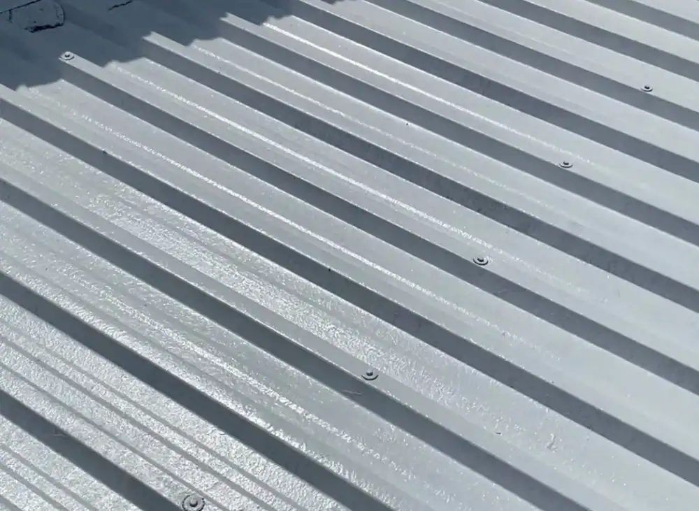 Close-up of silver metal roof panels with ridges and screws.