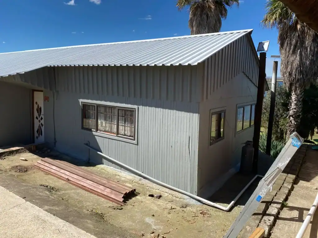 Contemporary metal house with windows and palm trees in the background.